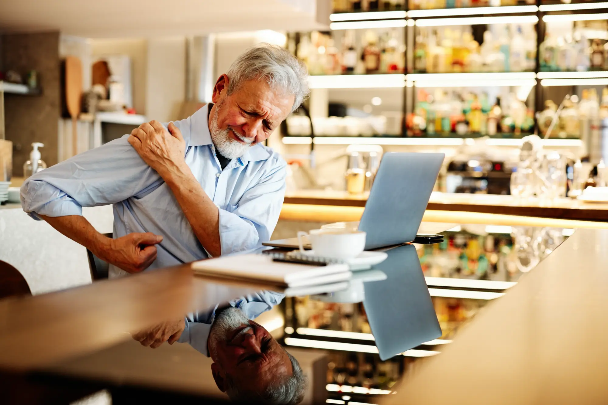 Senior man working at a table with arthritis in the shoulder