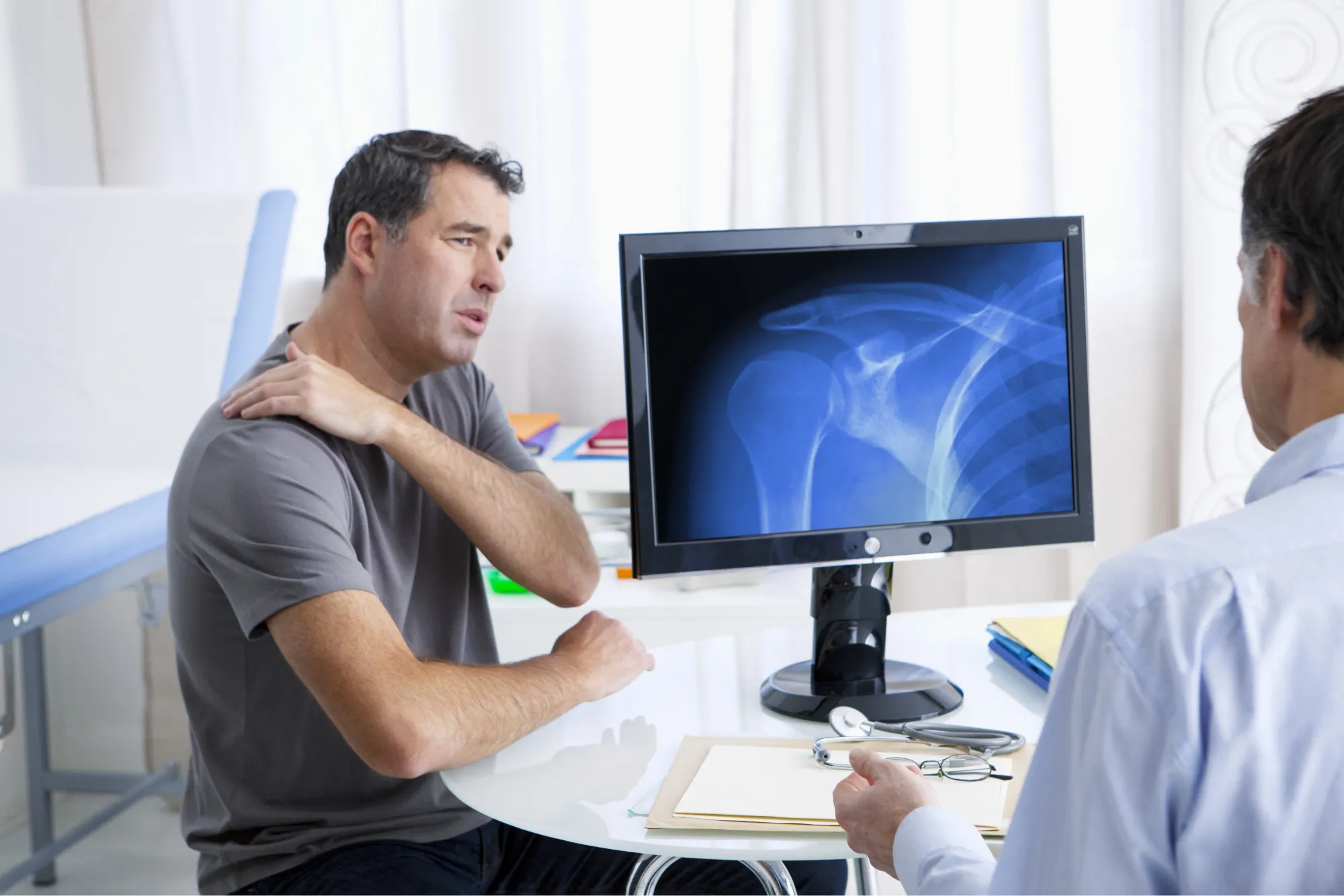 patient consulting his surgeon about getting reverse or total shoulder replacement.