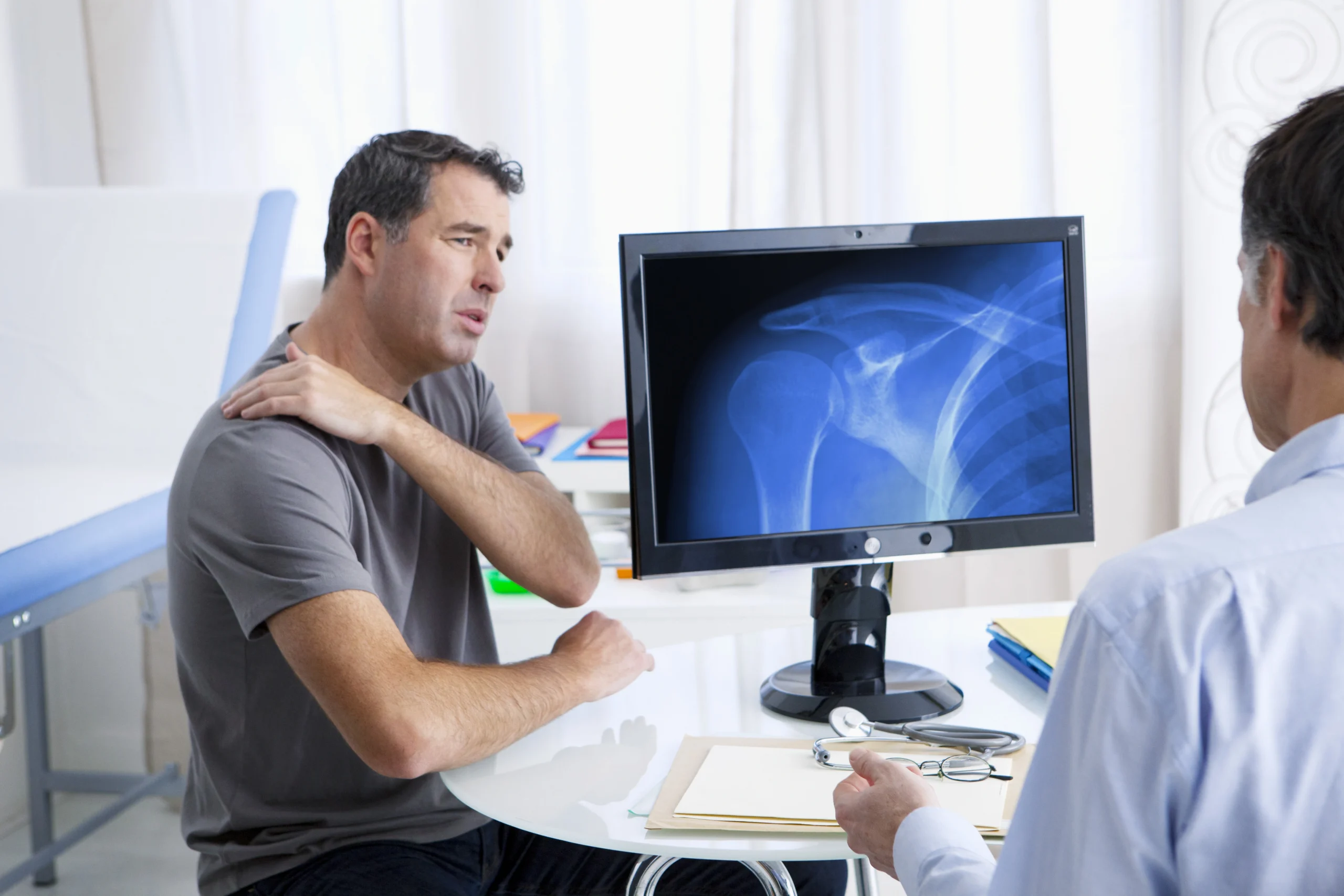 patient consulting his surgeon about getting reverse or total shoulder replacement.